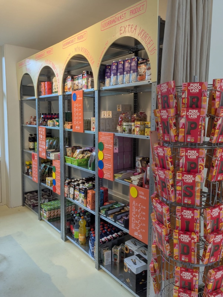Schappen met voorraadkastproducten onder beschilderde bogen, met prijsborden per kleur